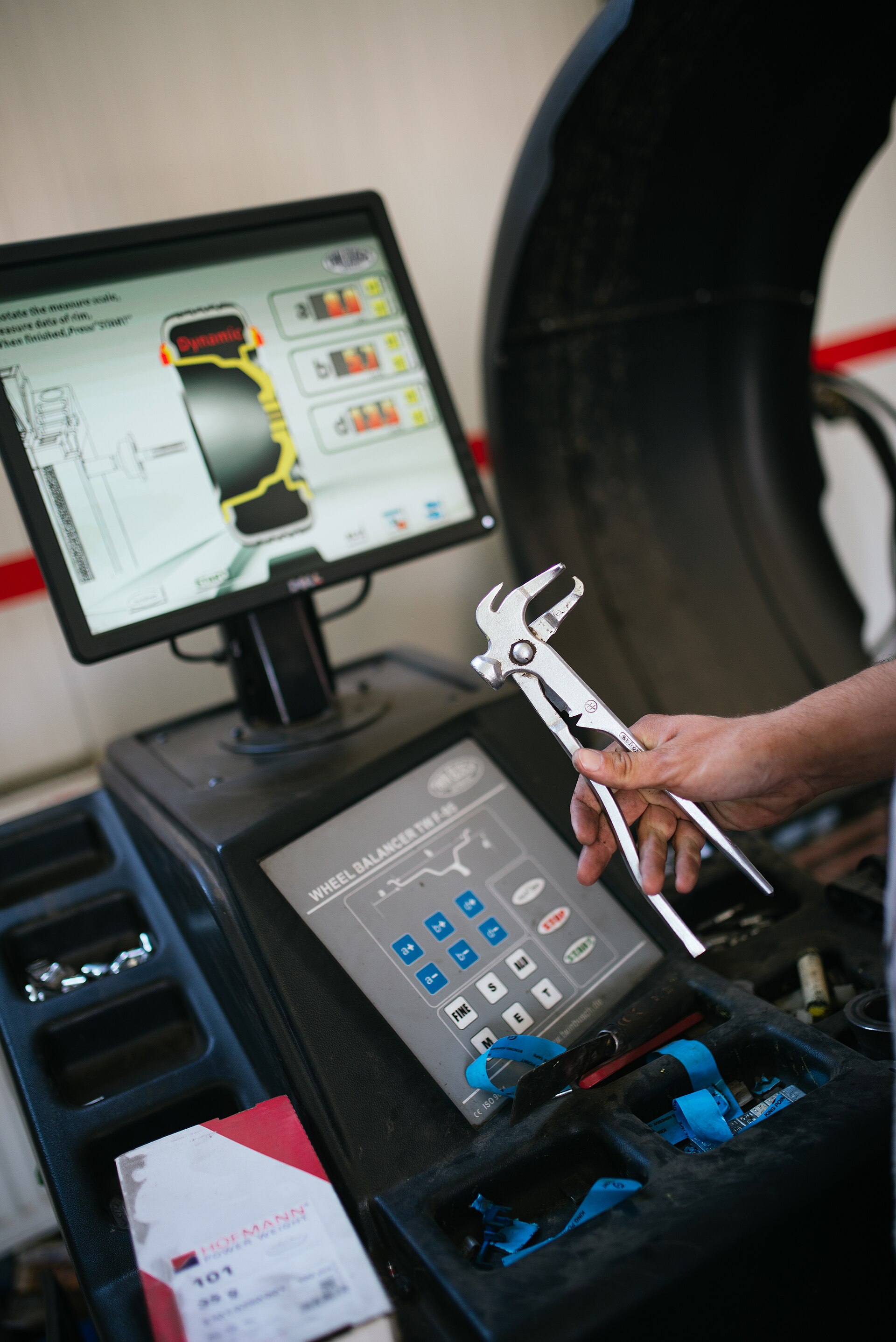 Dłoń mechanika przy komputerowym stanowisku do obsługi kół